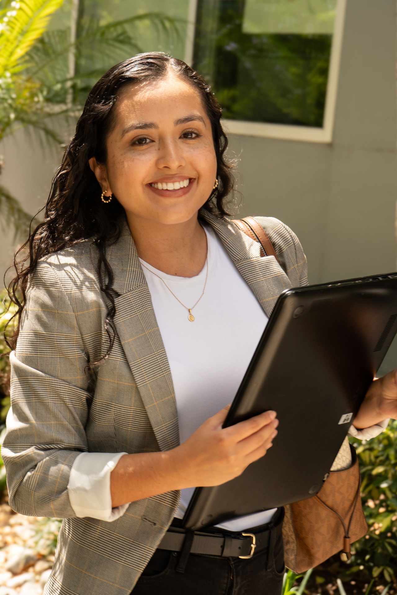 Mariana Franco, SHRM-certified career coach, smiling outdoors holding a laptop